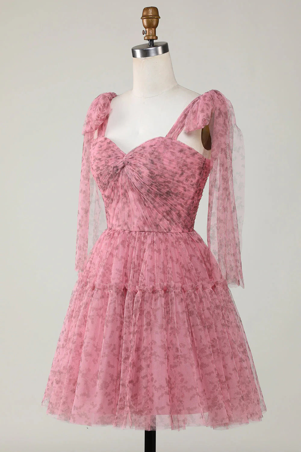 Model wearing a blush printed tulle short dress, highlighting the fabric detail and flow.