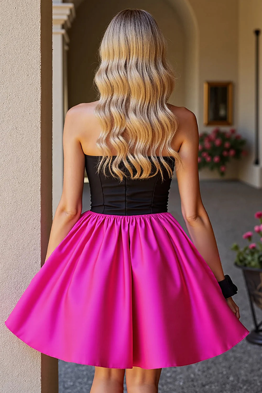 Back view of a model in a black and fuchsia strapless A-line mini dress.