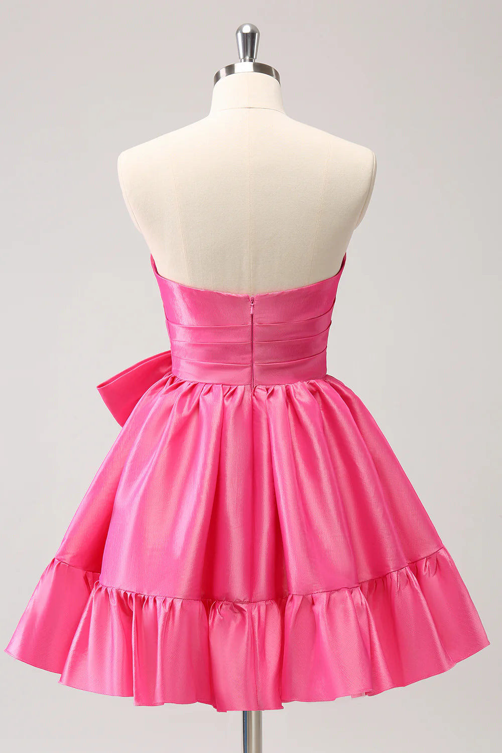 Side view of a model in a hot pink A-line strapless pleated short dress with a bow.