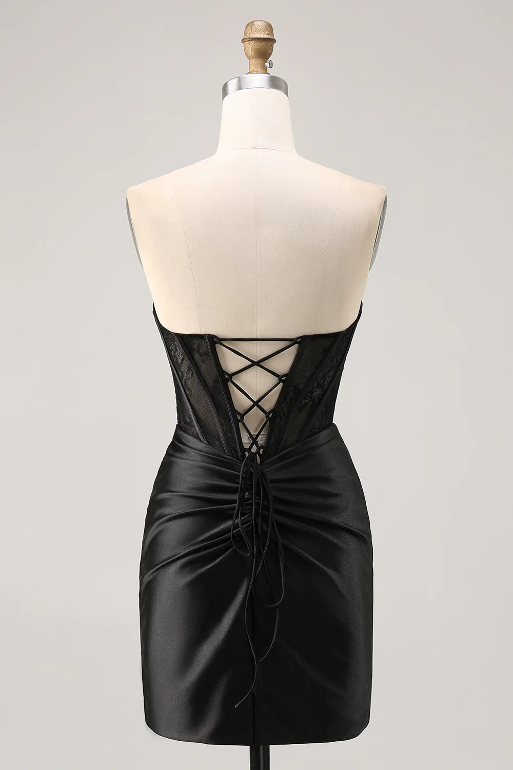 Model wearing a black strapless satin ruched bodycon dress, side view.