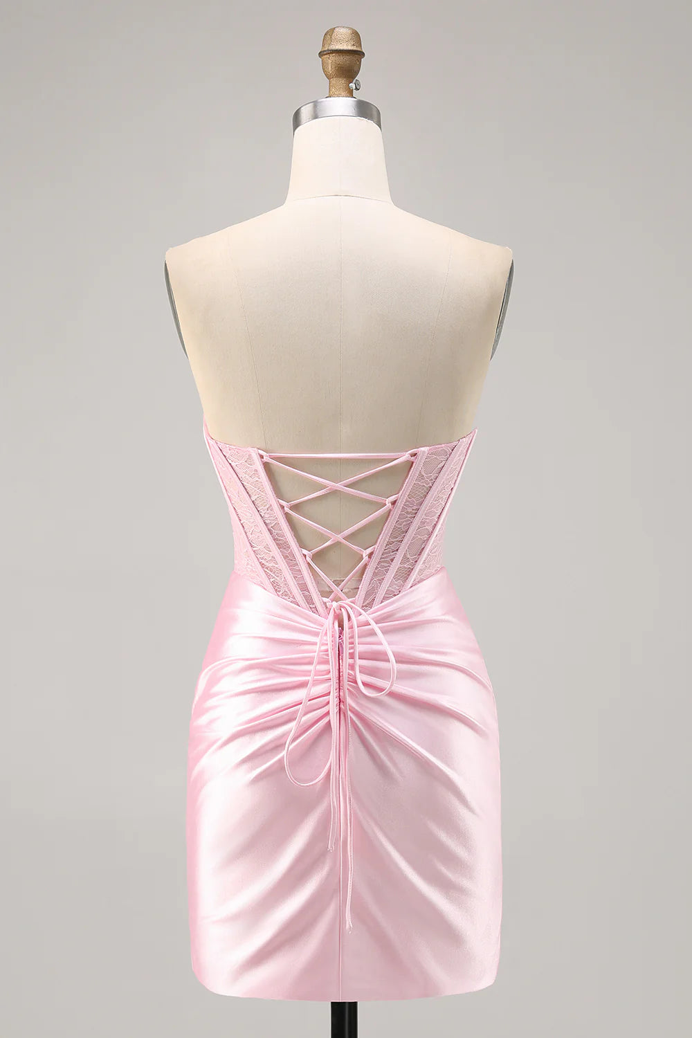 Back view of a model wearing the pink satin strapless ruched bodycon dress.