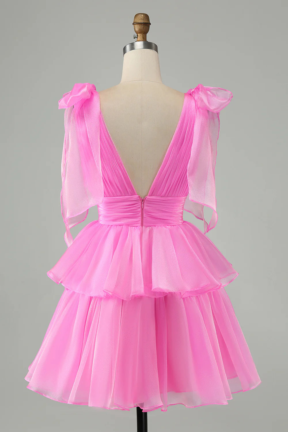 Back view of a model in a hot pink A-line V-neck backless pleated tiered short homecoming dress.
