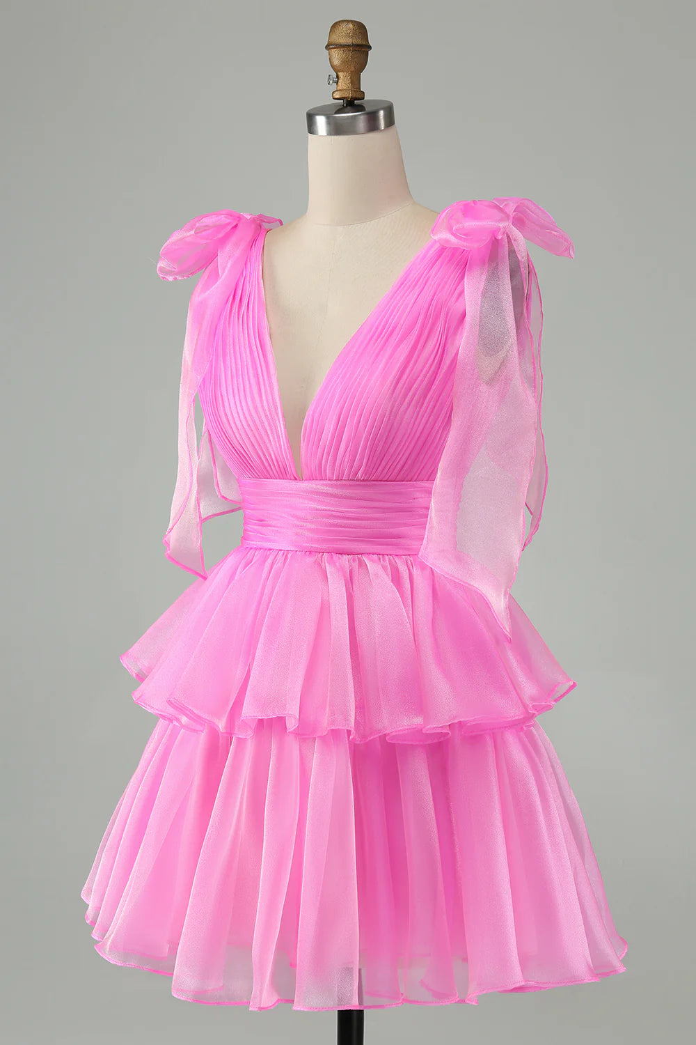 Side view of a model in a hot pink A-line V-neck backless pleated tiered short homecoming dress.