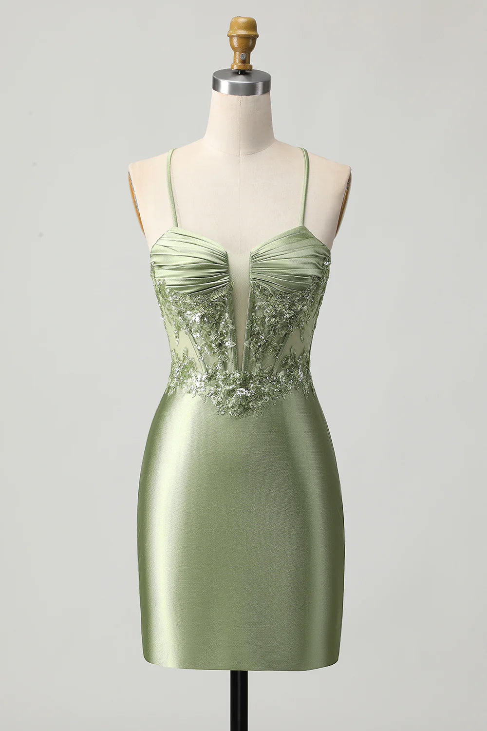 Model wearing a sage green short satin homecoming dress with appliques and lace-up back.