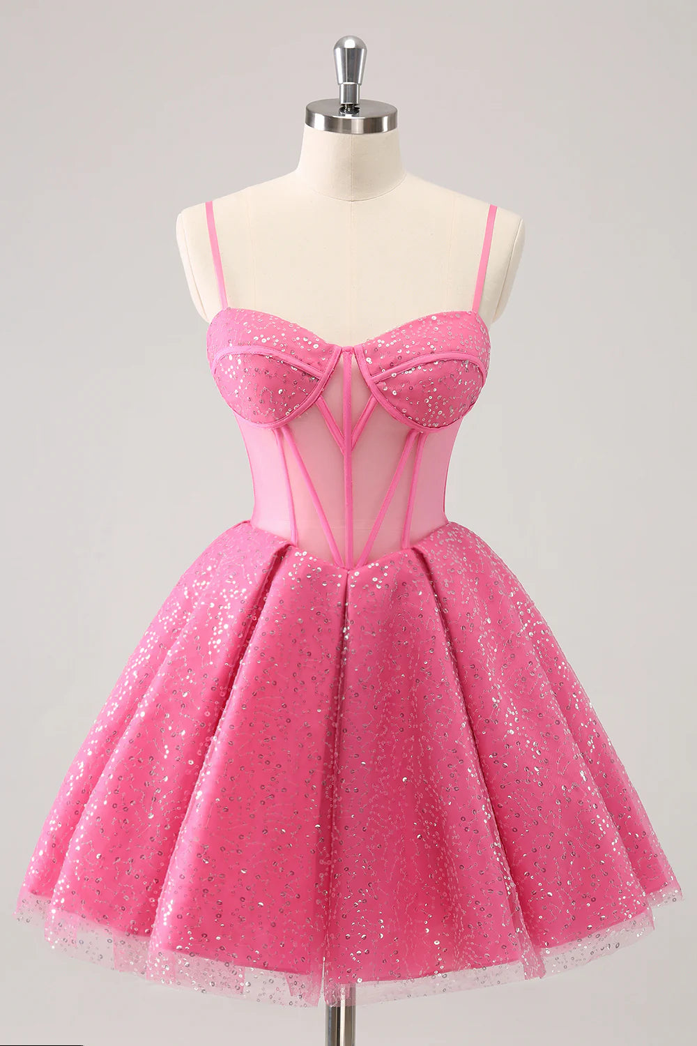 Model wearing a sparkly pink A-line short homecoming dress with spaghetti straps and corset detail.