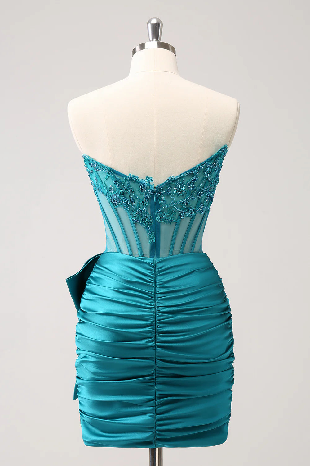 Back view of a peacock strapless homecoming dress, showing corset lacing and short pleated skirt.