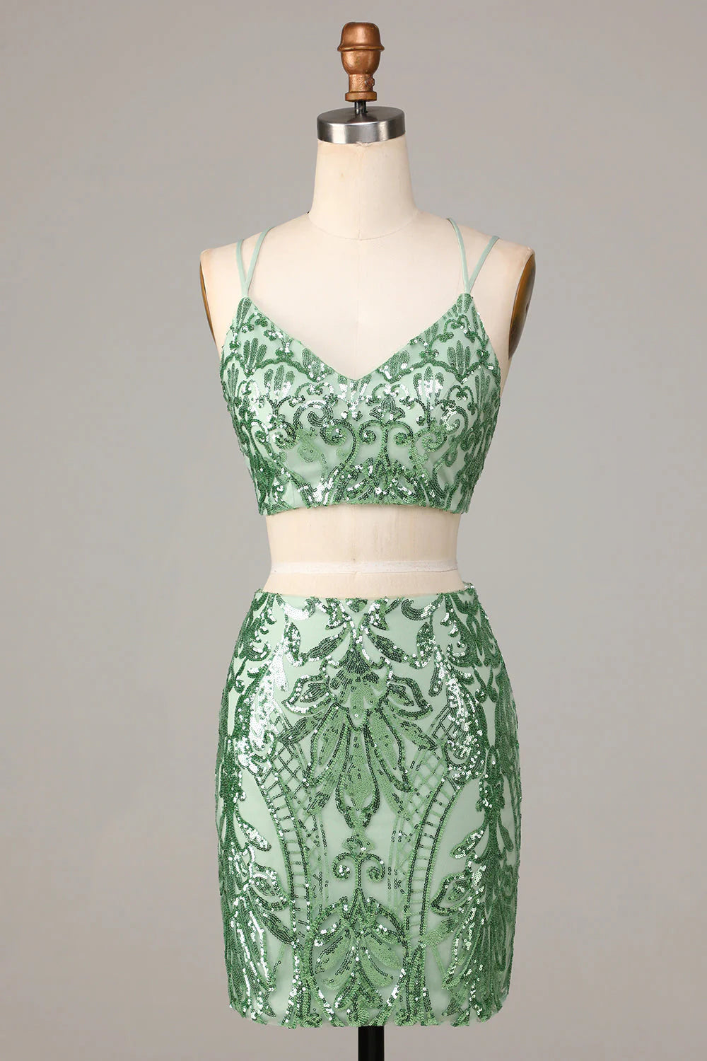 Model wearing a dazzling green two-piece sequin short homecoming dress with spaghetti straps.