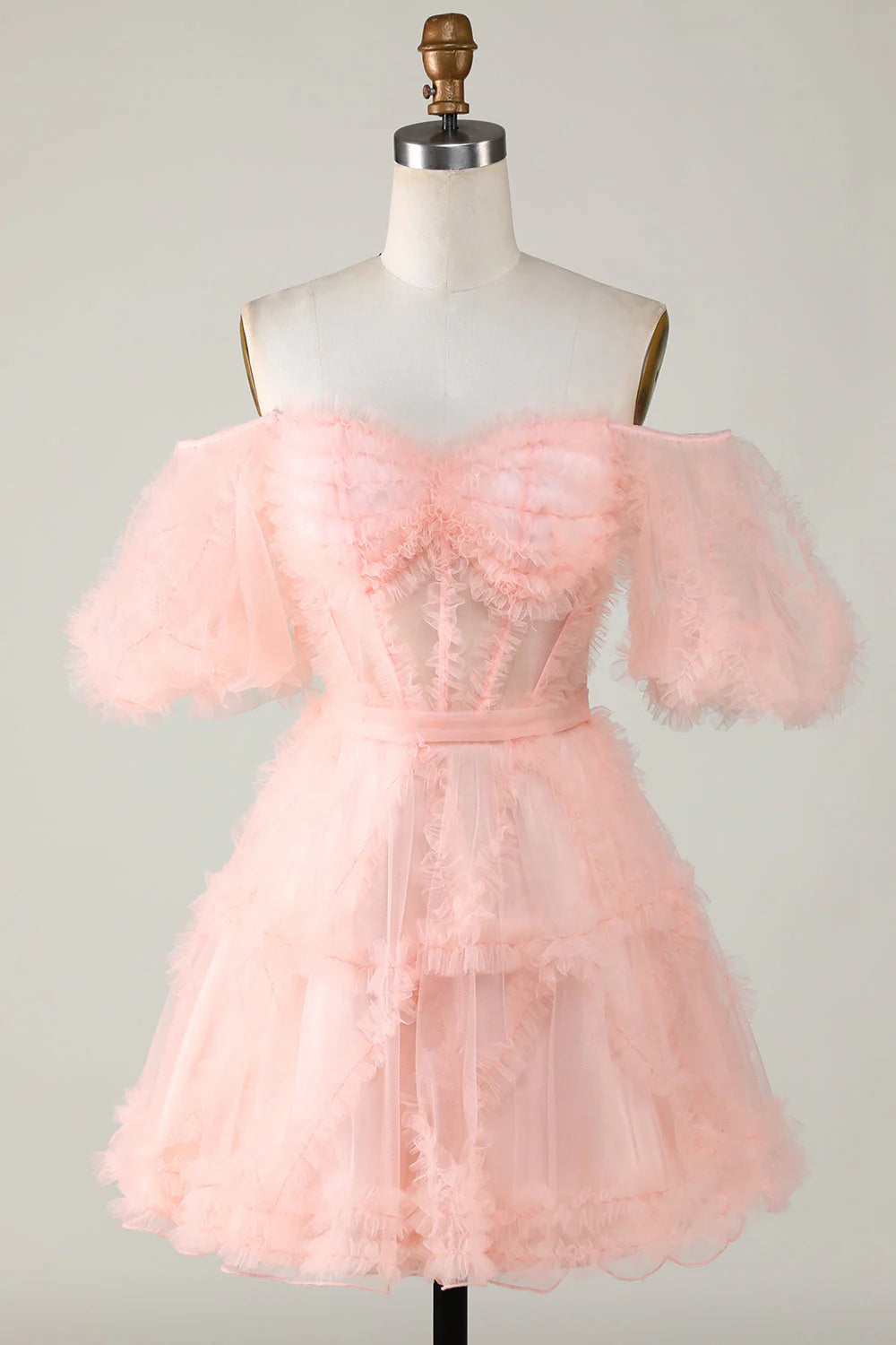Front view of a model wearing a blush A-line off-shoulder short tulle homecoming dress.