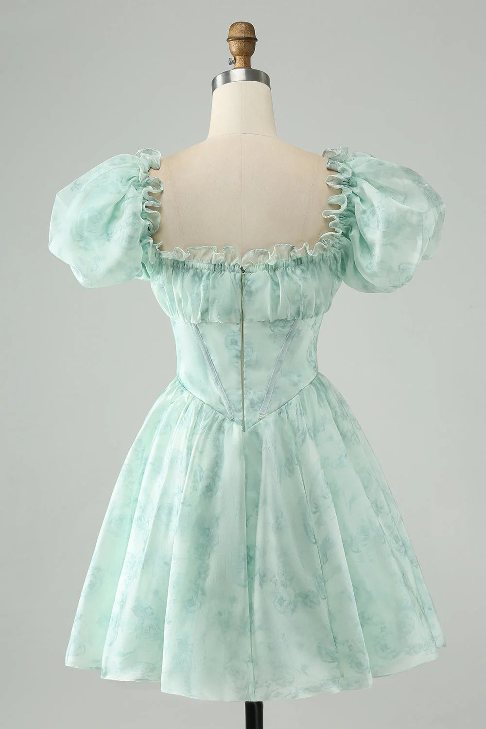 Model wearing a light green A-line floral short homecoming dress with ruffles, side view.