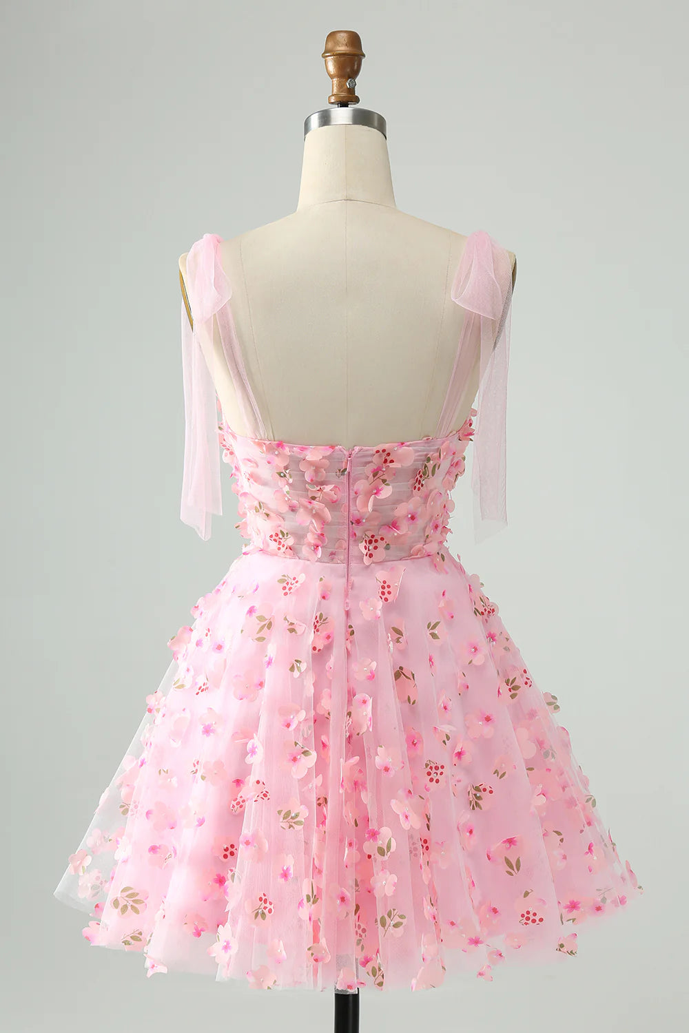Back view of a pink A-line short homecoming dress showing corset detail and flowing skirt.