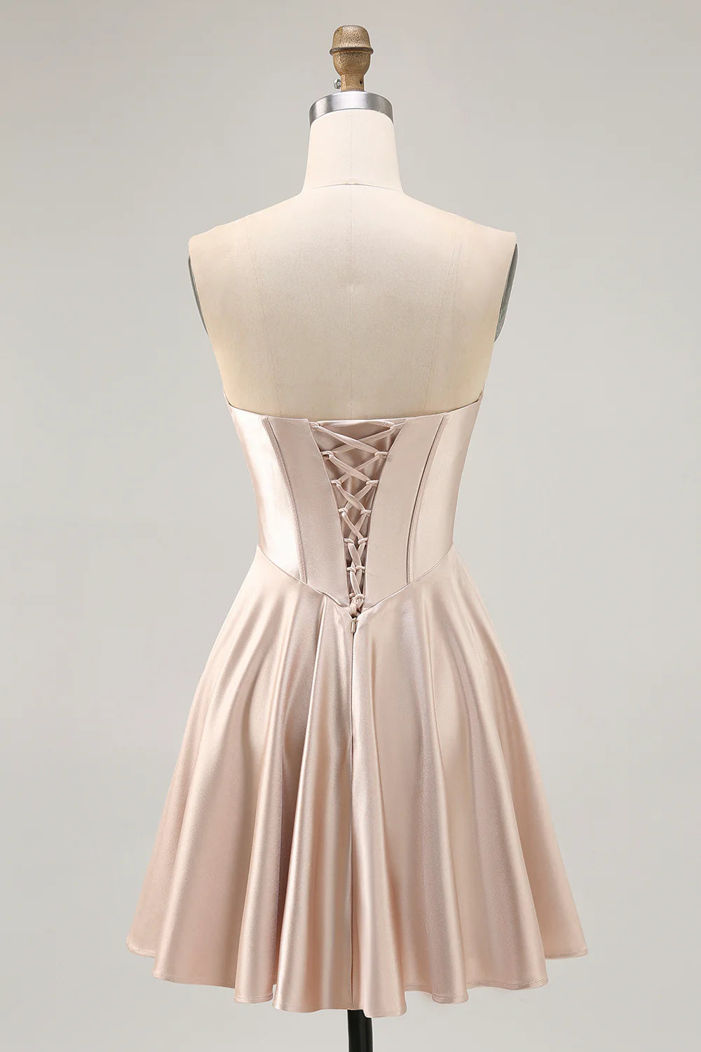 Side view of a model in a champagne A-line strapless dress, showing ruched bodice and flowing skirt.