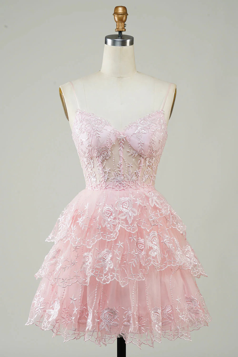 Model wearing a pink A-line short homecoming dress with a corset bodice and tiered skirt.