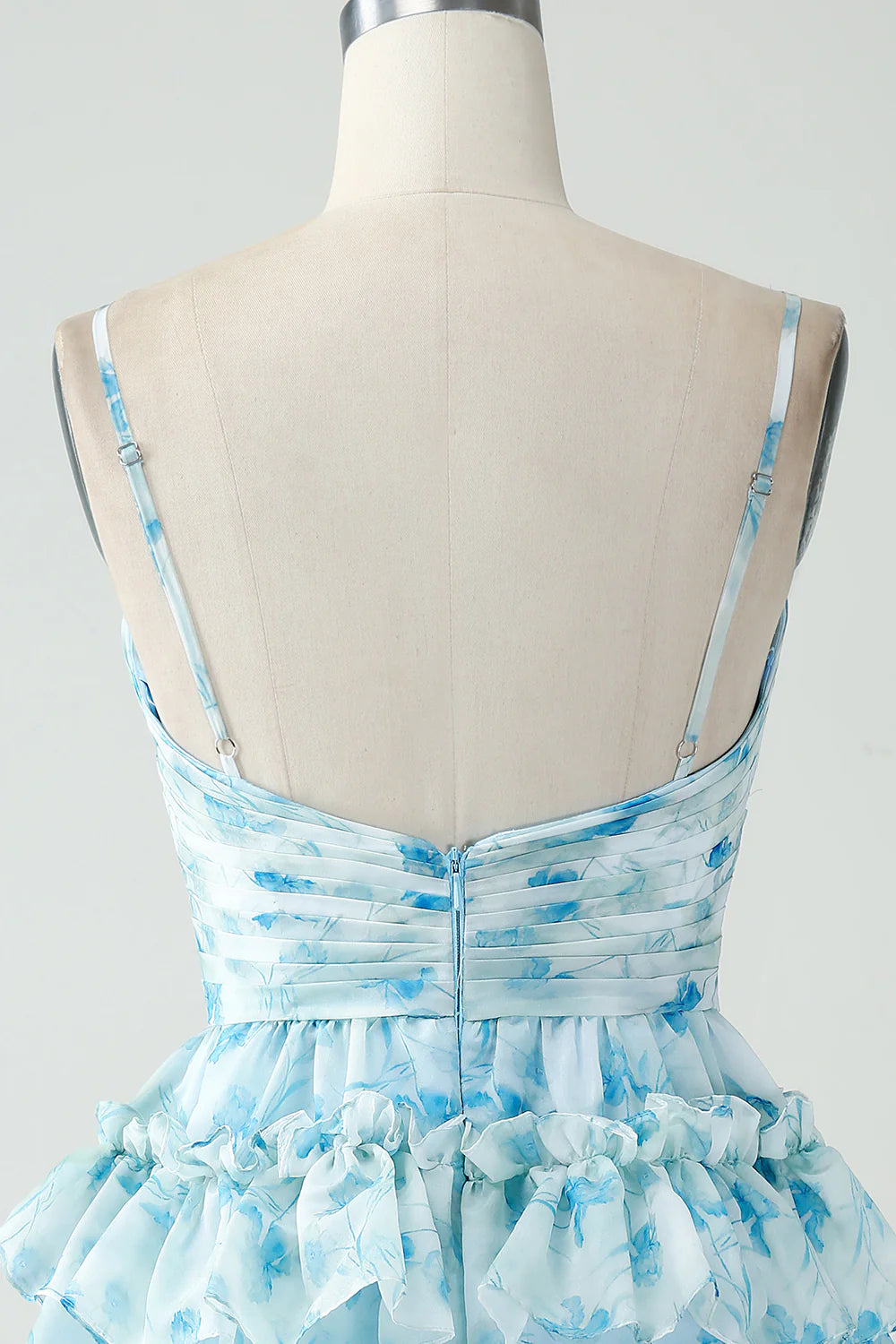 Model posing in a blue floral A-line tiered pleated short homecoming dress.