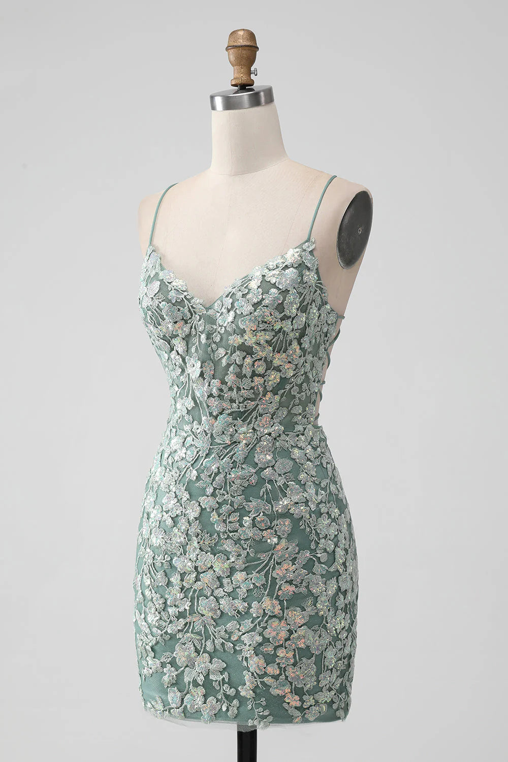 Model wearing a grey green bodycon short homecoming dress with sequin appliques and a lace-up back.
