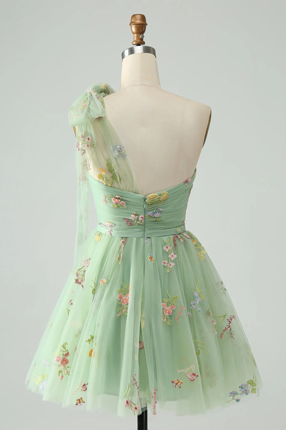 Back view of light green one shoulder tulle dress with delicate floral details.
