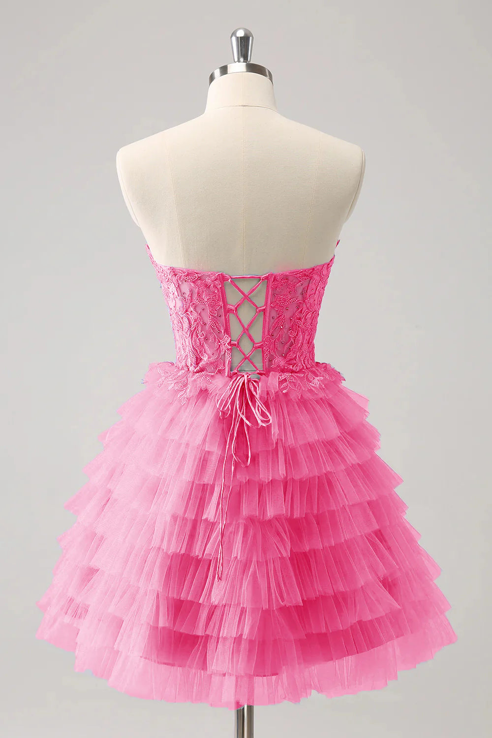 Back view of a pink A-line formal gown, highlighting the lace-up corset detail.