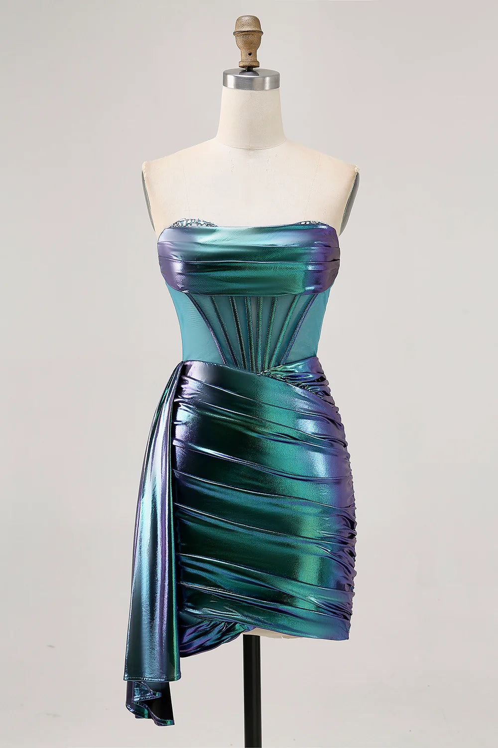 Model wearing a metallic green strapless corset ruched short homecoming dress with a side cape.