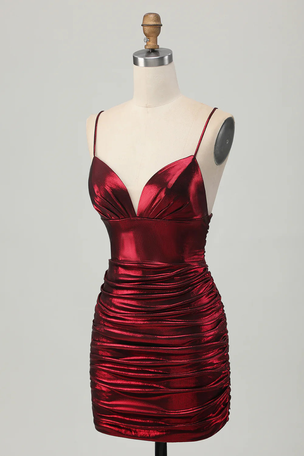 Side profile of the metallic burgundy satin short dress, showcasing ruched detailing.