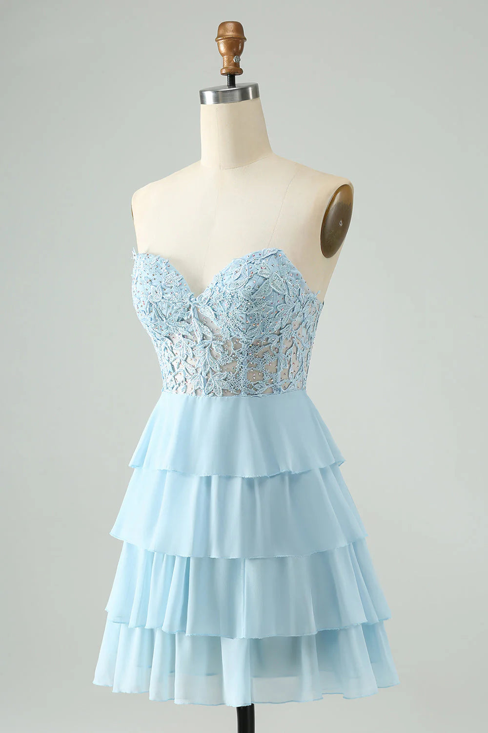 Close-up of appliques on a light blue sweetheart tiered short homecoming dress.