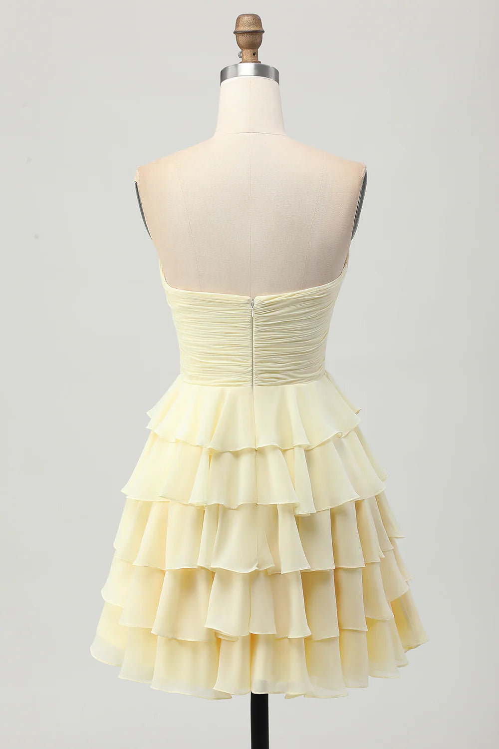 Side view of the light yellow ruched strapless homecoming dress.
