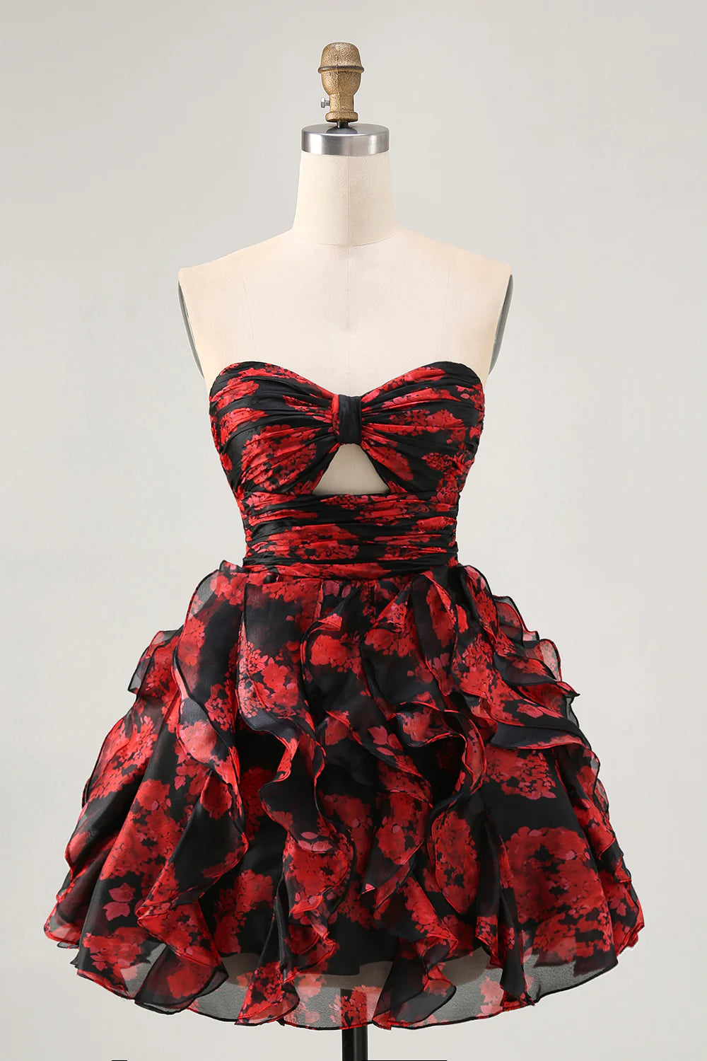 Model wearing a black and red floral strapless A-line short homecoming dress with ruffles and cut-outs.
