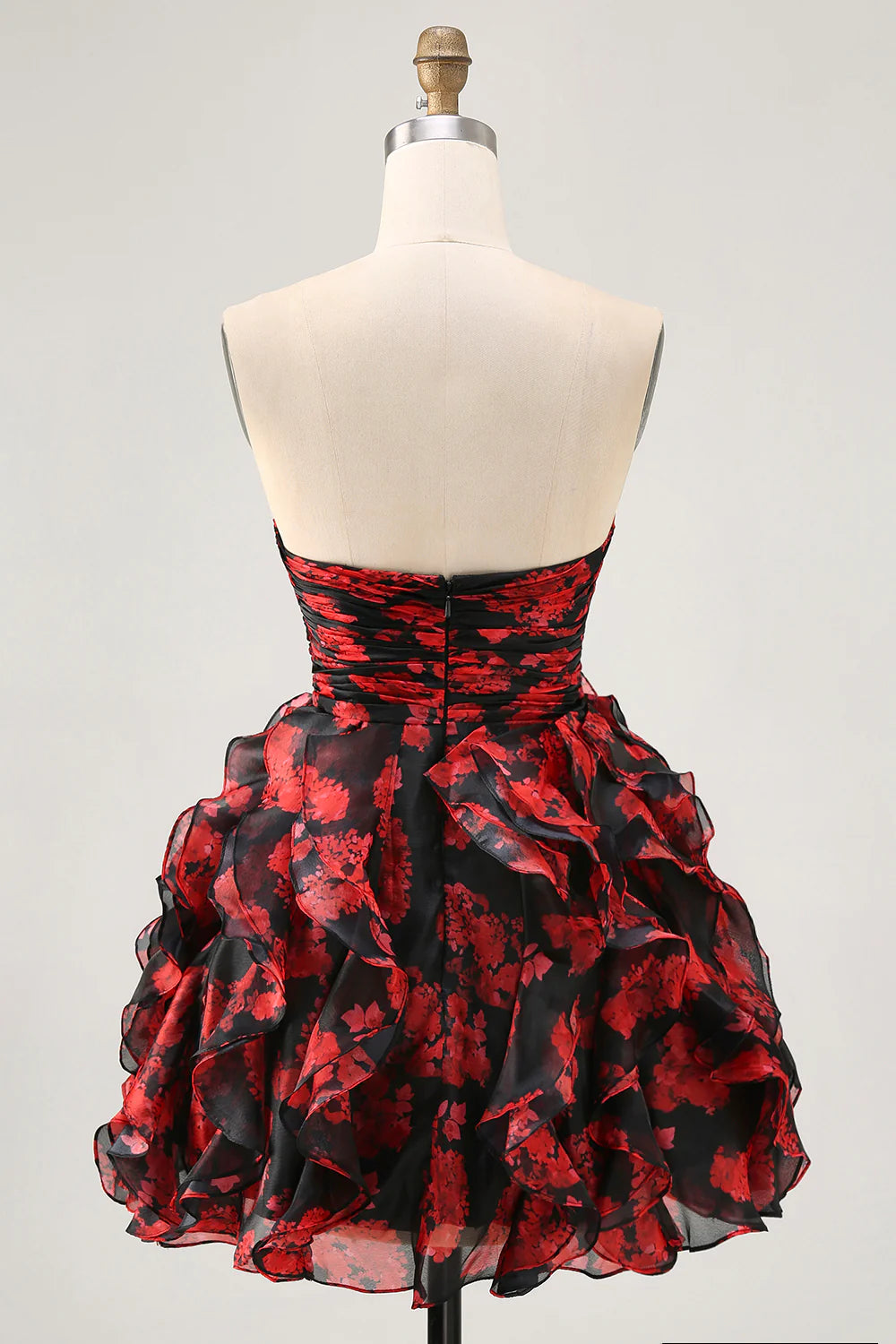 Model posing in a black and red floral strapless short homecoming dress, showcasing back details.