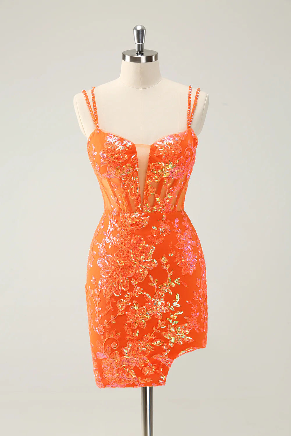 Model in a glitter orange short homecoming dress with spaghetti straps and a side slit.