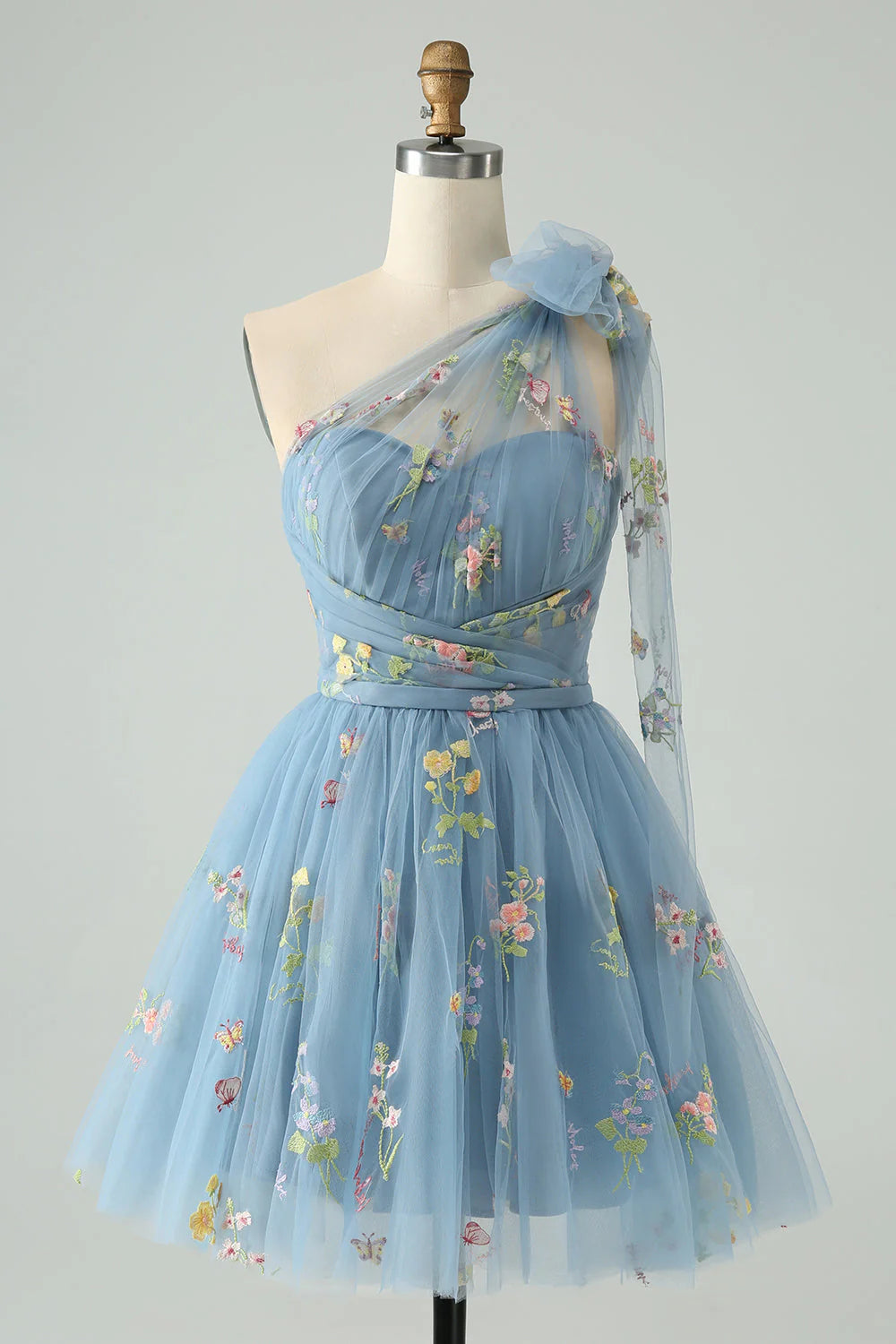 Detailed view of the one-shoulder neckline and floral embellishments on the grey blue dress.
