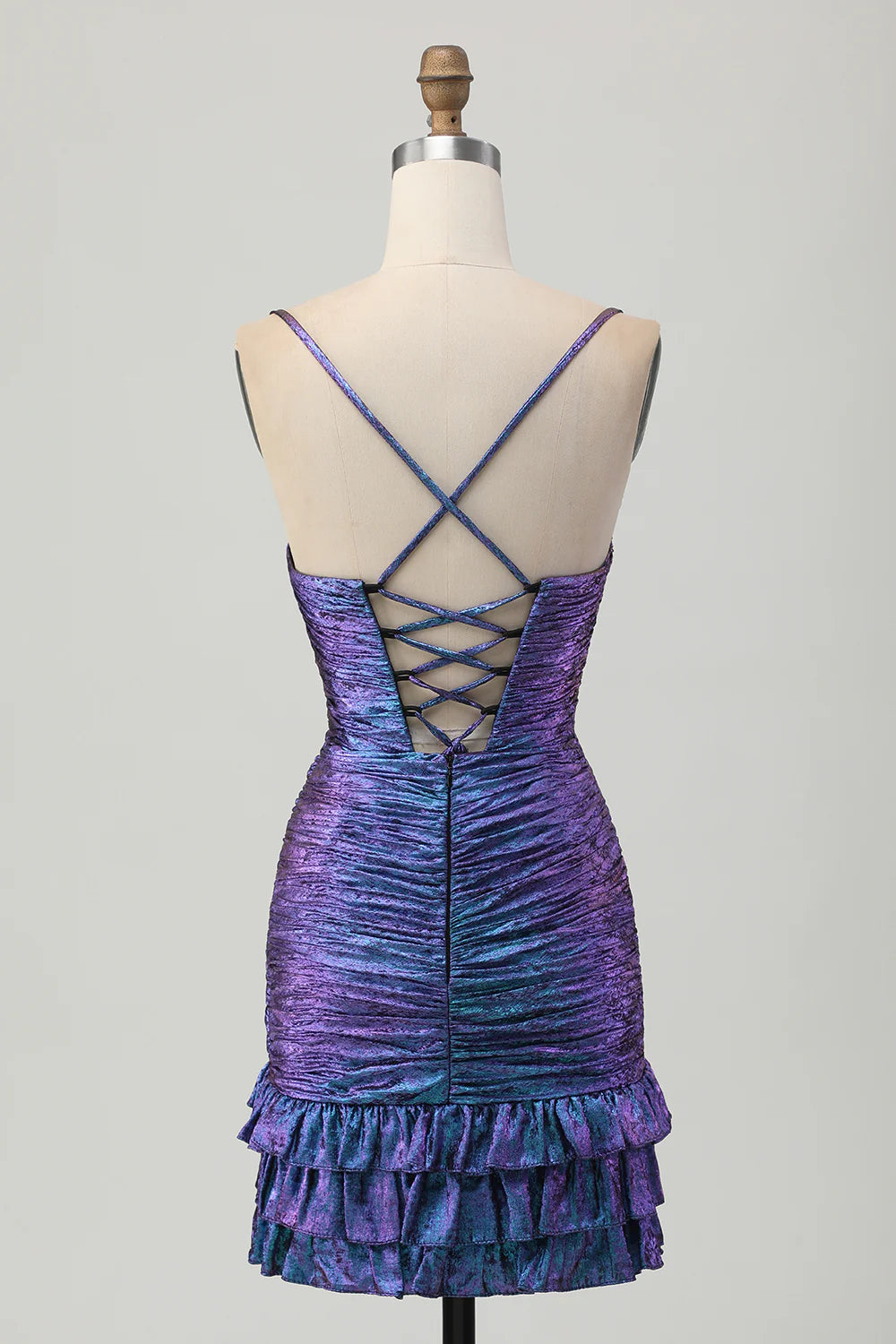 Model wearing a shimmering blue-purple bodycon ruched short homecoming dress with ruffles, side view.