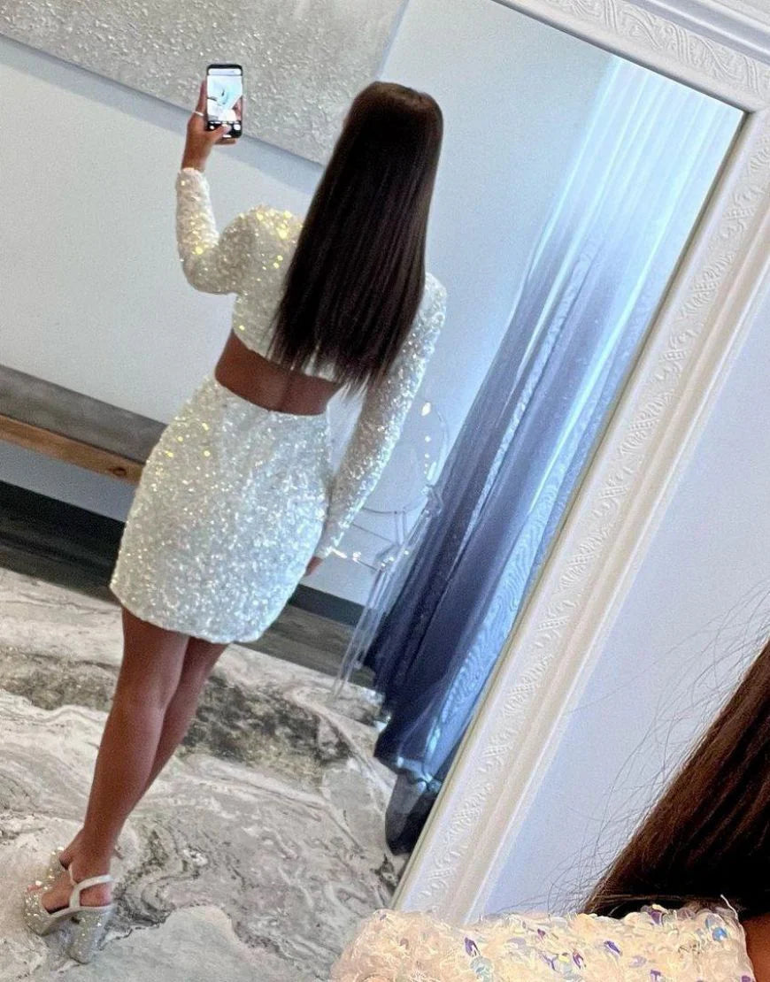 Back view of white sequin long sleeve dress showing cutout waist detail.