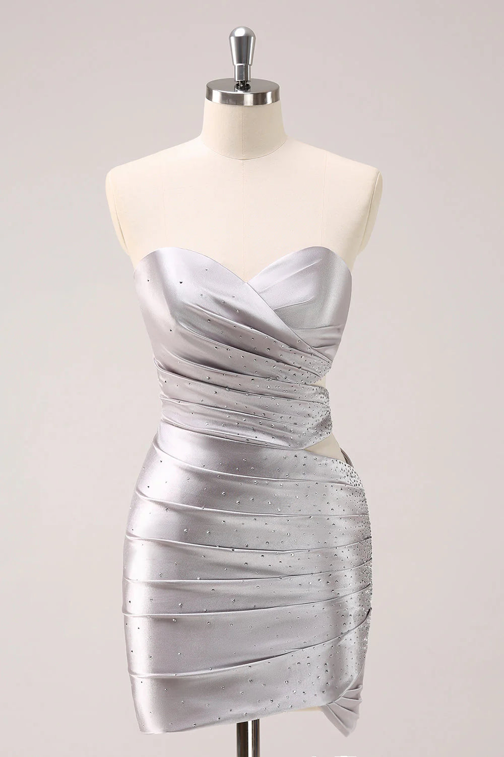 Model wearing a silver strapless pleated mini homecoming dress with cut-out details and beading.