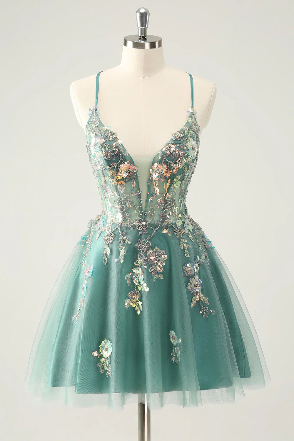 Model wearing a sparkling grey-green A-line homecoming dress with spaghetti straps and sequin appliques.