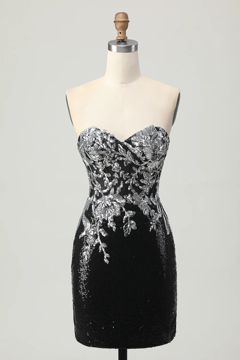 Model wearing a black and silver floral sequin short homecoming dress with a strapless sweetheart neckline.