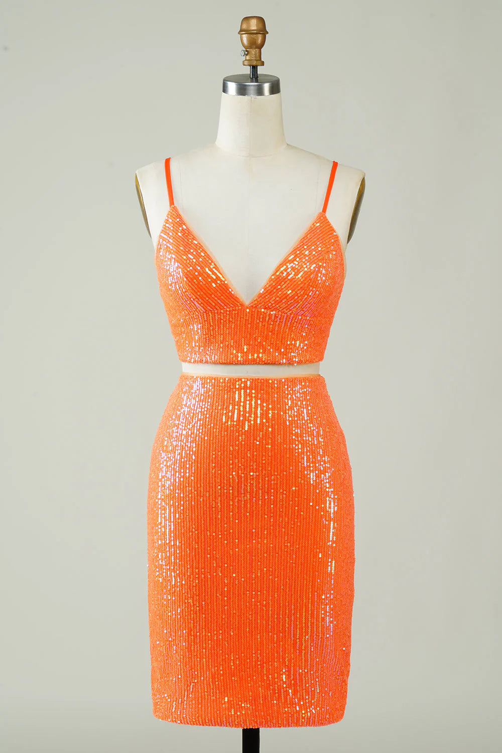 Model wearing a sparkling orange sequin two-piece V-neck homecoming dress with a fitted silhouette.