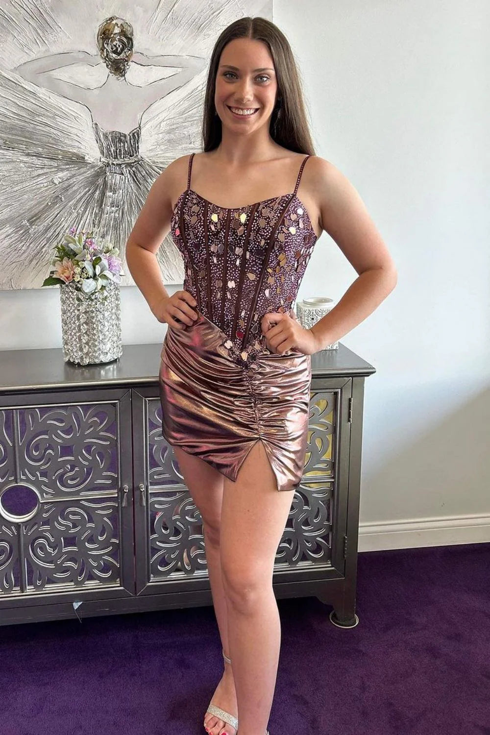 Model wearing a sparkly rose gold A-line homecoming dress with spaghetti straps, posing elegantly.