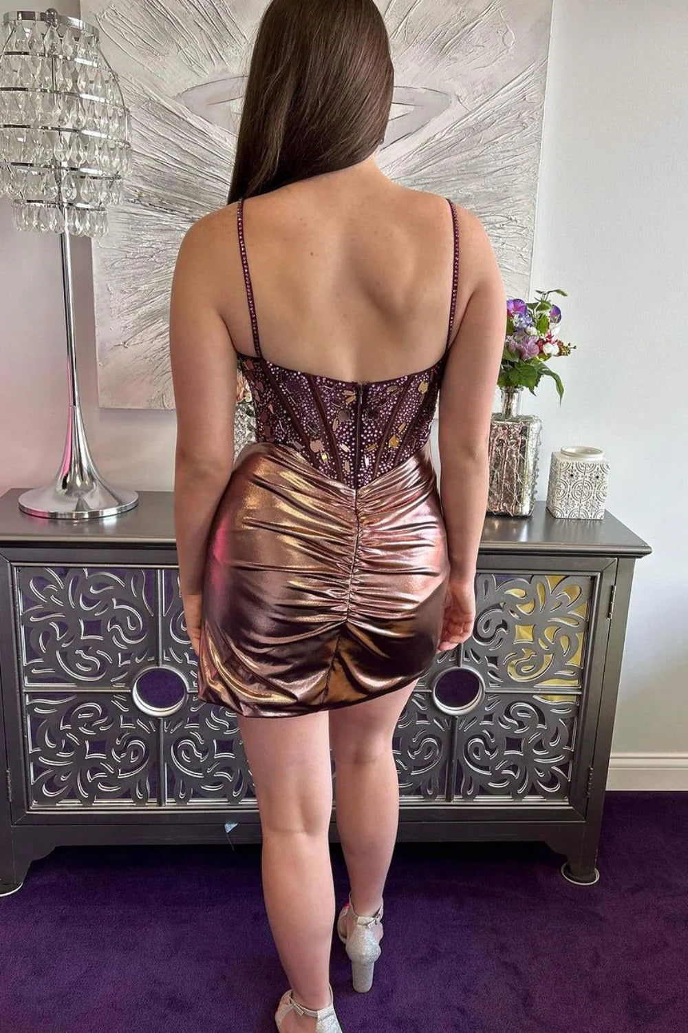 Back view of a model in a short rose gold sparkly homecoming dress, showcasing the delicate spaghetti straps.