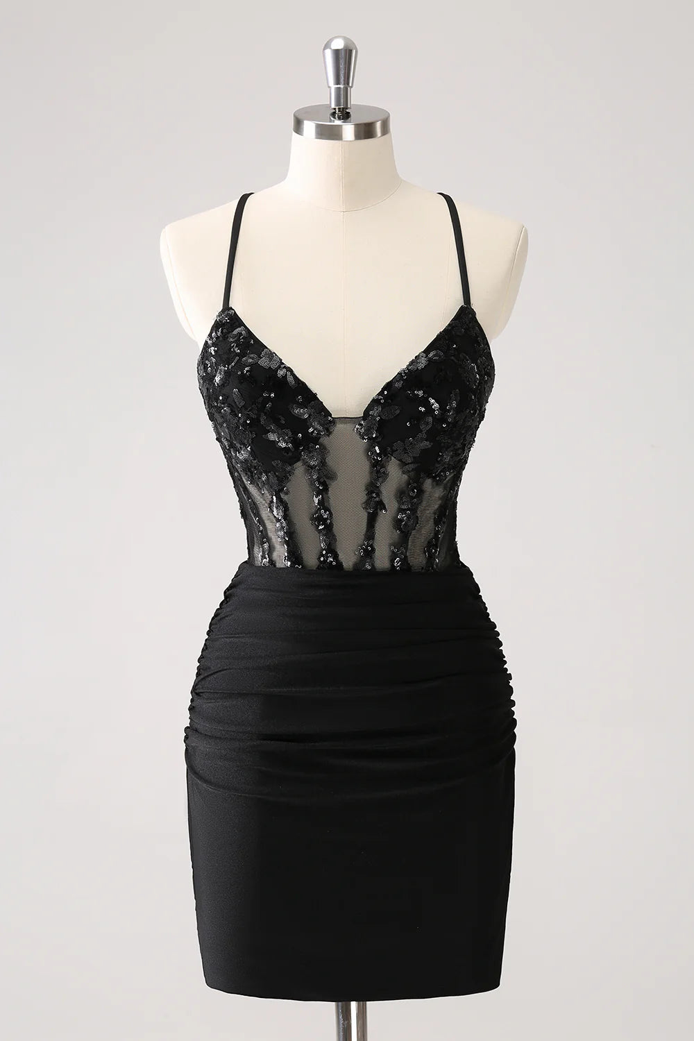 Model wearing a sparkly black sequin spaghetti strap homecoming dress with a lace-up back.