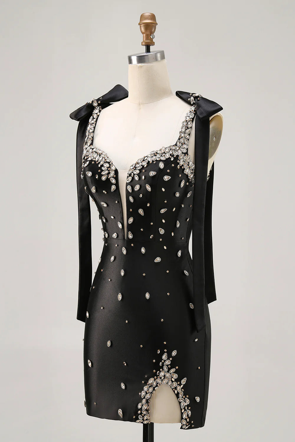 Model wearing a sparkly black bodycon dress with spaghetti straps and a side slit.