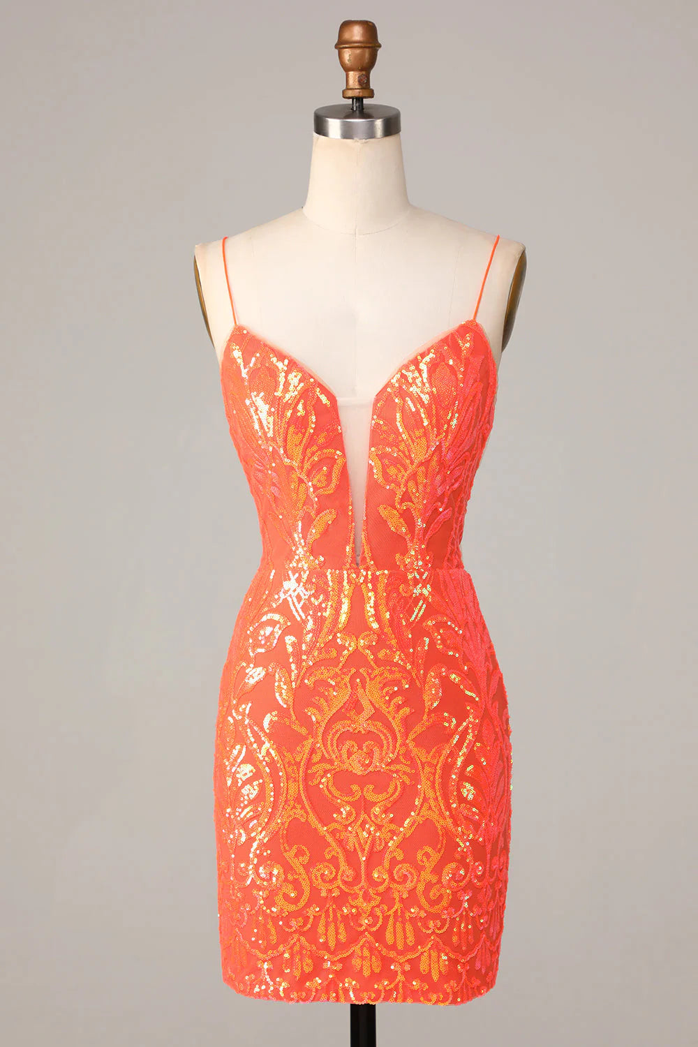 A woman wearing a sparkly orange bodycon short homecoming dress with spaghetti straps.