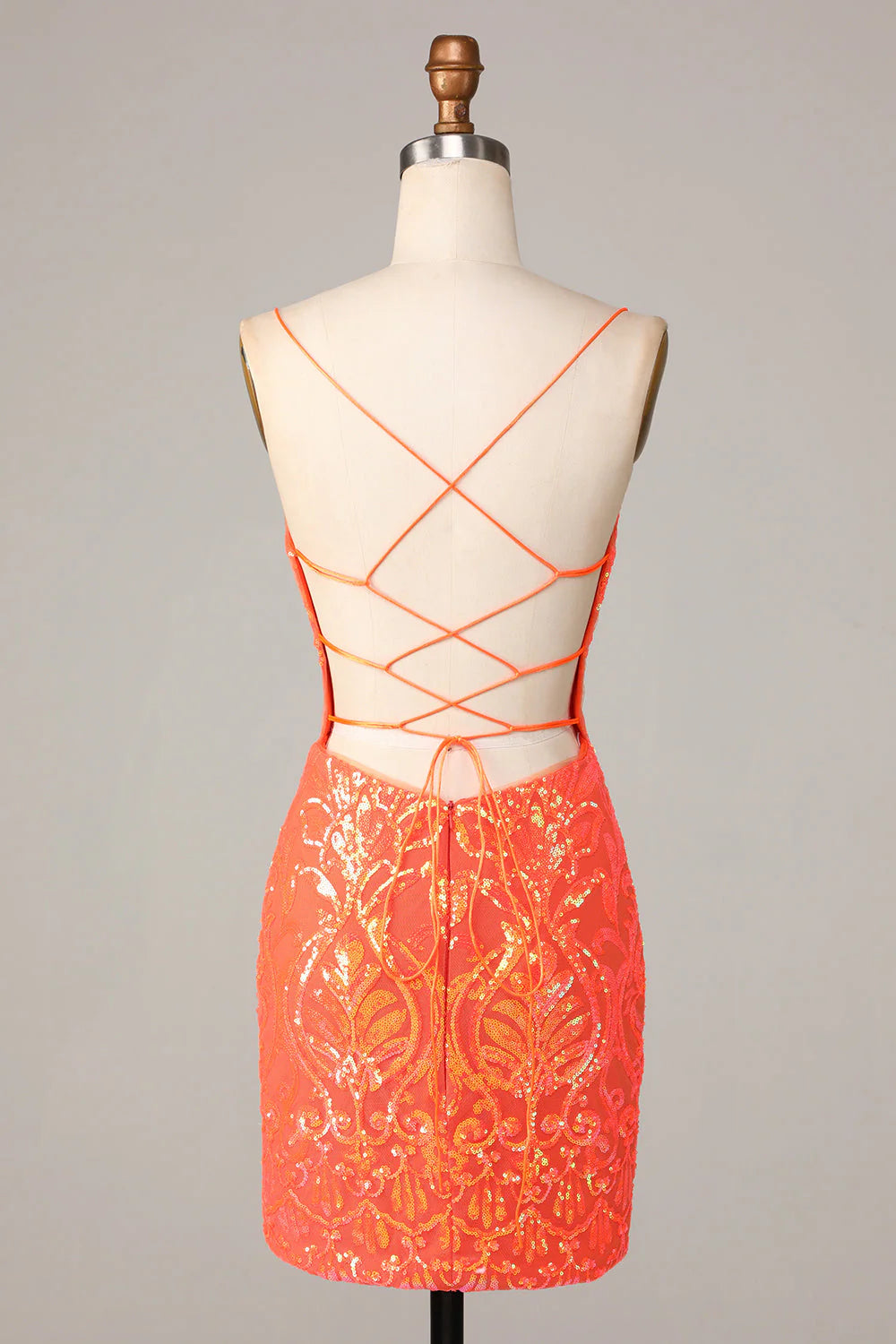 A woman posing in a sparkly orange sequin bodycon dress, showing the back detail.