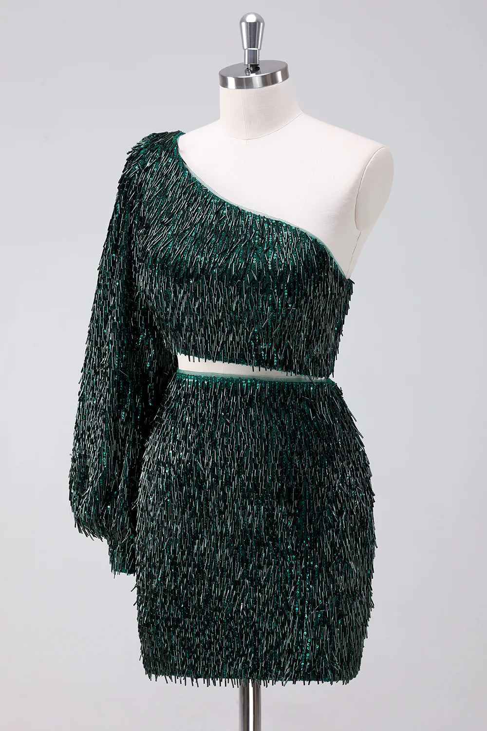 Model wearing a sparkly fringed dark green one-shoulder short homecoming dress, posing elegantly.