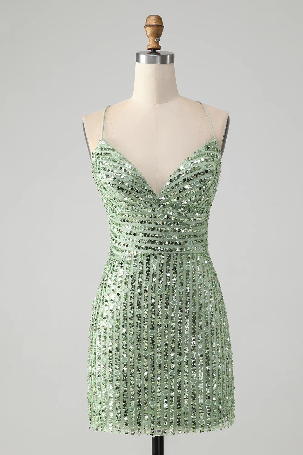 Model wearing a sparkly green sheath homecoming dress with a criss-cross back.