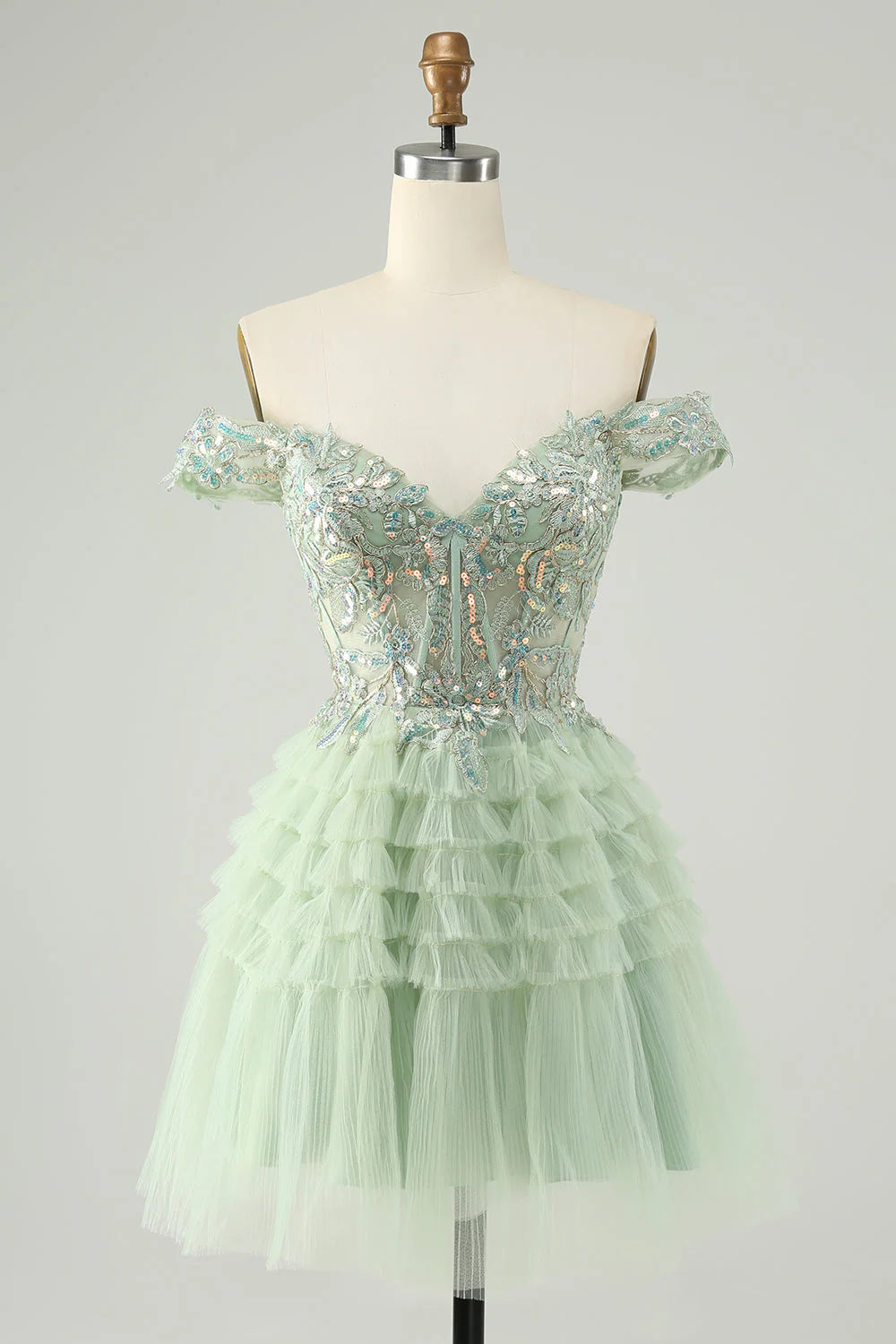Model wearing a sparkly light green A-line off-shoulder tulle homecoming dress with sequins.