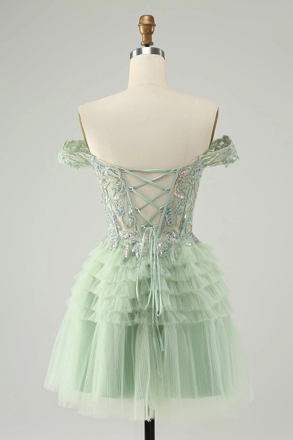 Back view of a sparkly light green A-line off-shoulder tulle homecoming dress with corset detail.