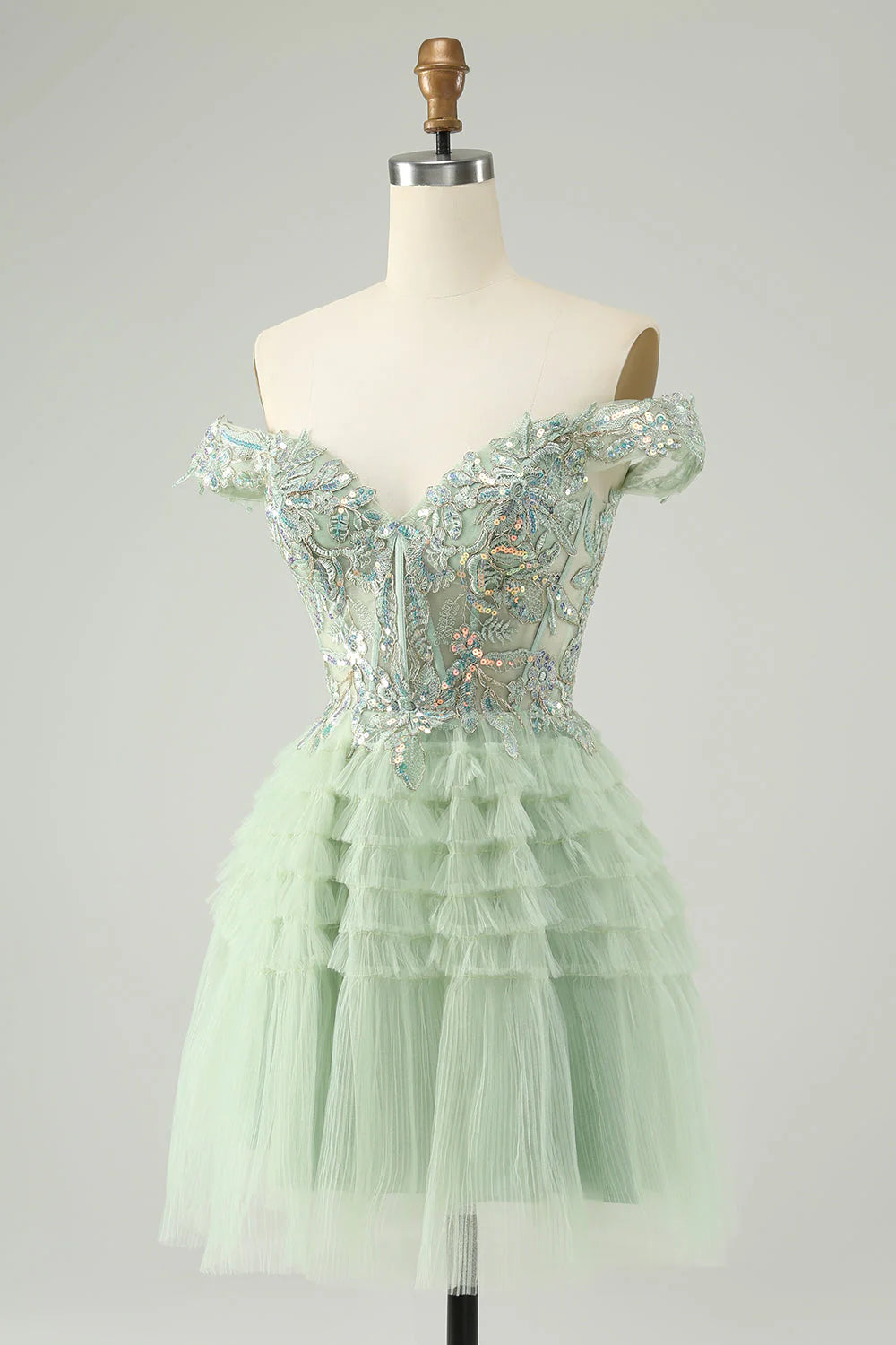 Close-up of the sequin and tulle fabric on a light green off-shoulder homecoming dress.