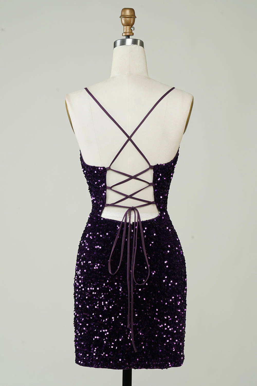 Side view of a model in a tight sparkly purple sequin backless dress with a leg slit.