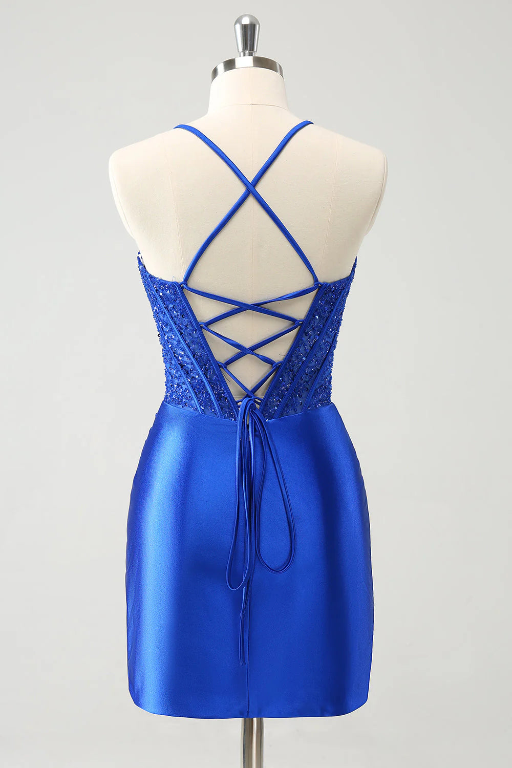 Back view of a sparkly royal blue sequin short homecoming dress, showing the pleated skirt and corset lacing.