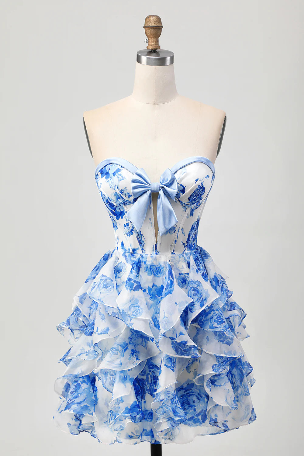 Full view of a white and blue floral strapless A-line tiered homecoming dress with a bow.